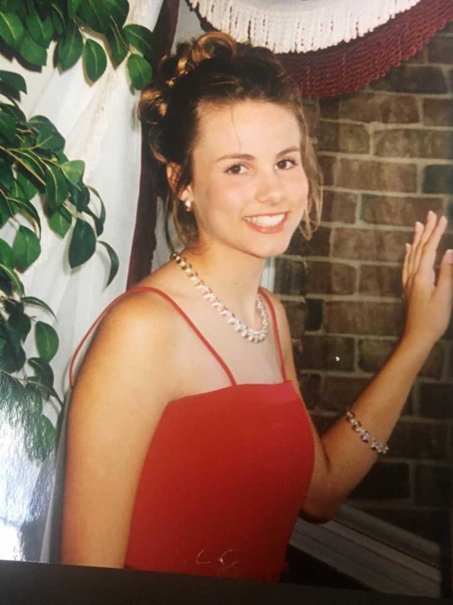 Woman who tells people not to pluck their eye brows stands smiling in red dress