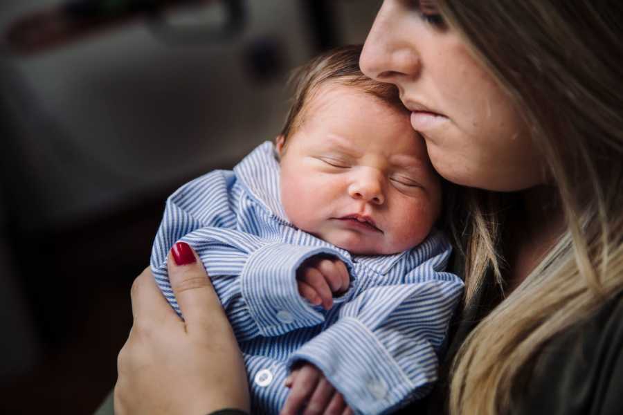Mother holds her baby boy close to chest with her eyes closed