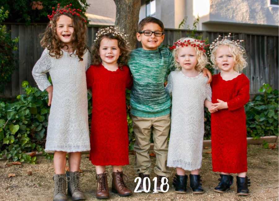Five young siblings dressed for Christmas stand outside with their arms wrapped around each other