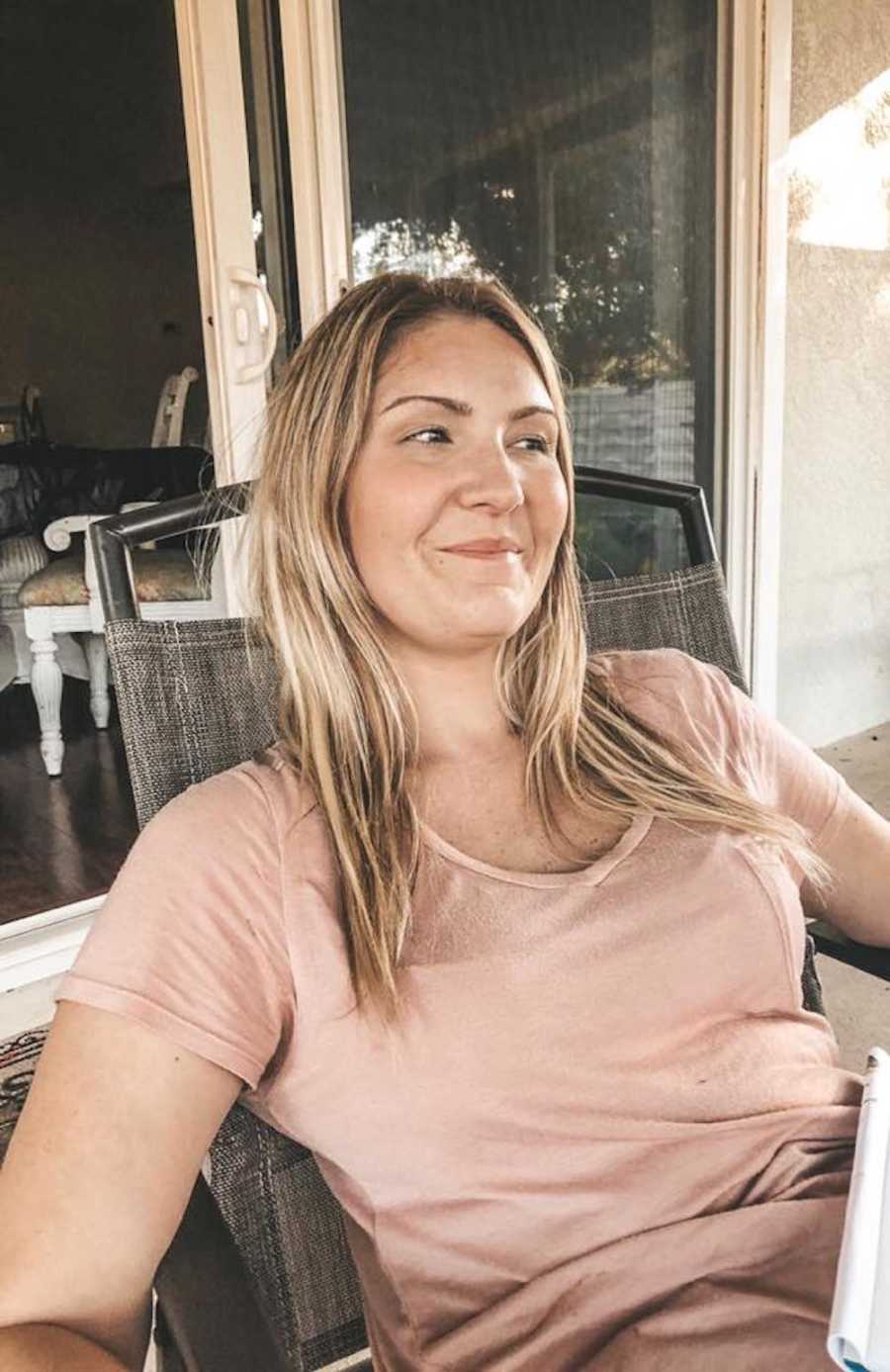 Woman who lost her mother sits smiling at outdoor table 
