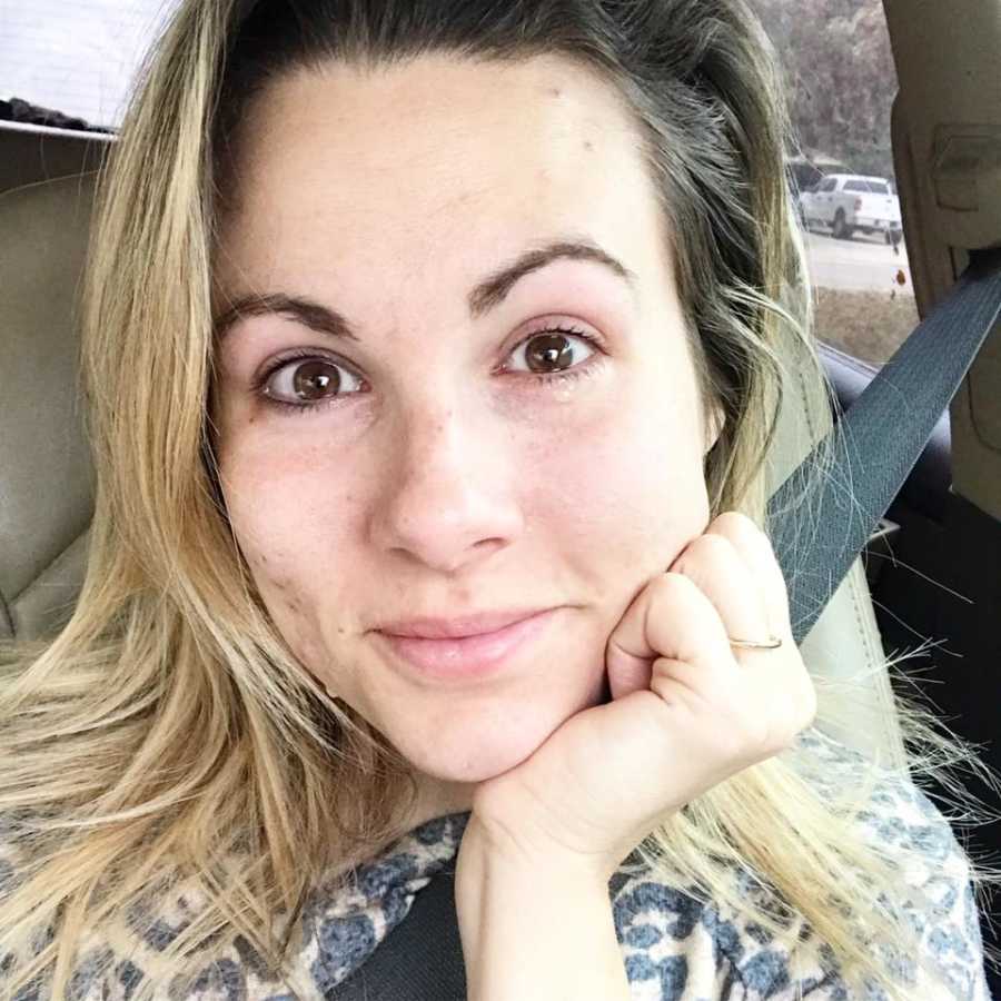 Mother who is exhausted smiles in selfie she takes in her car with tears in her eyes