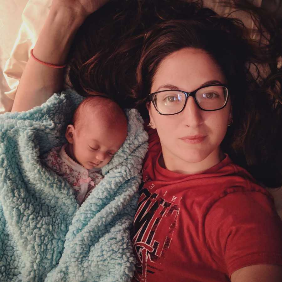 Mother lays down in selfie with baby asleep at her side