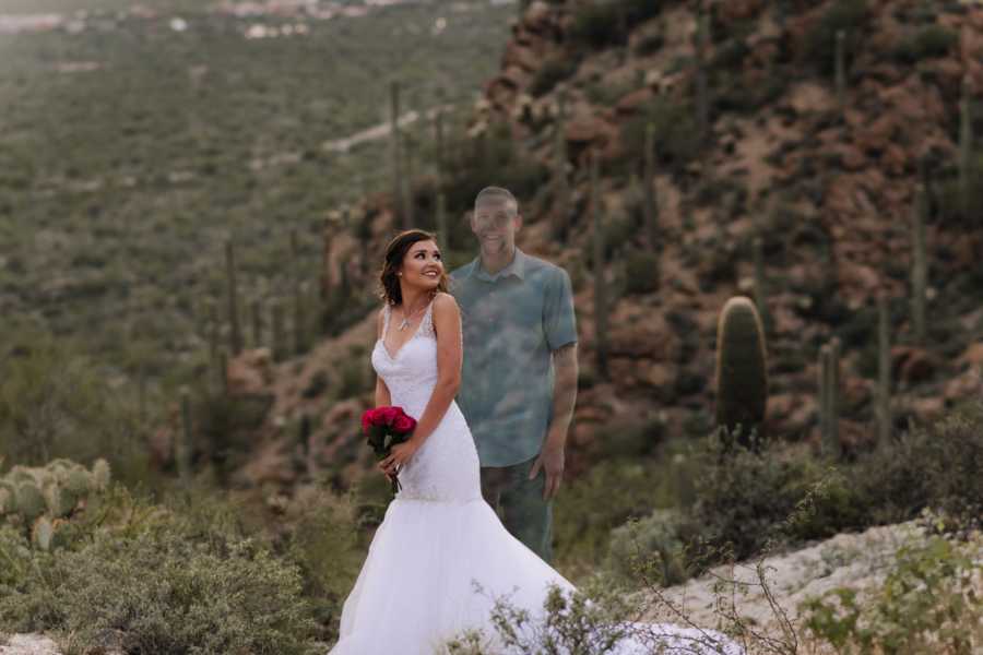 Woman in wedding dress smiles as she looks over her shoulder where ghost of her late fiancee stands in photoshoot