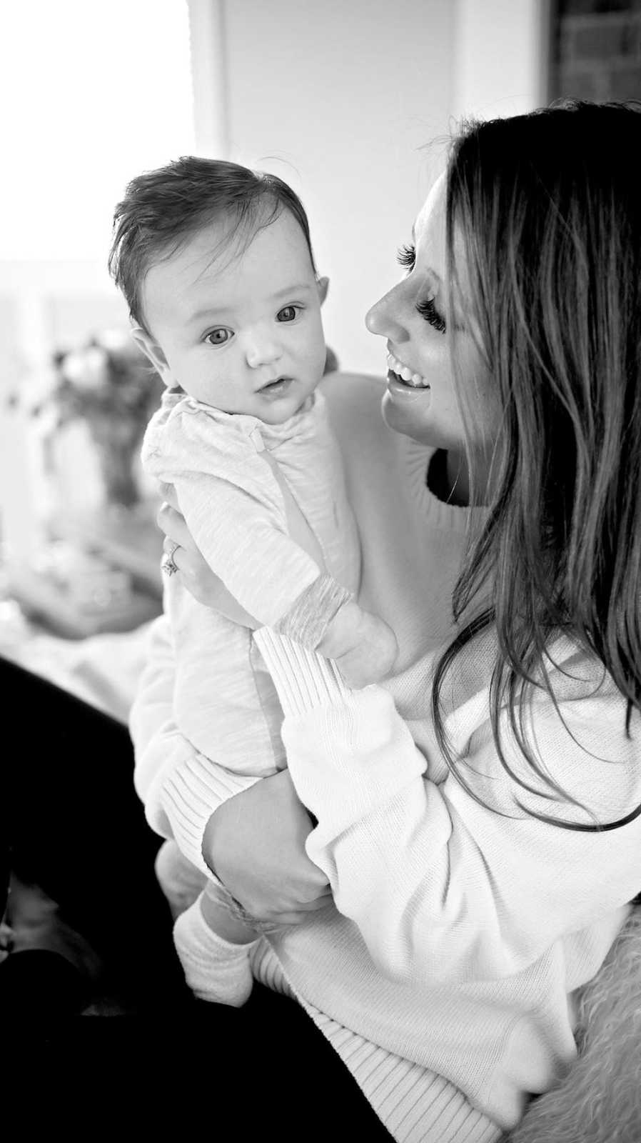 Mother who gets upset with her children smiles at baby she holds in her arms