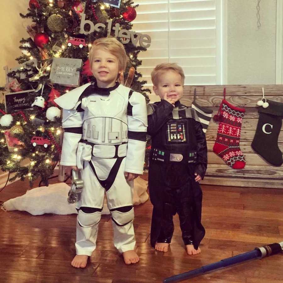 Toddler boys standing in home in front of Christmas tree in Star Wars costumes