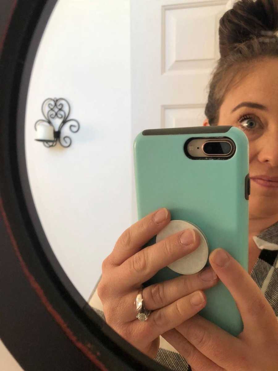 Mother with high functioning anxiety holds up phone in mirror selfie