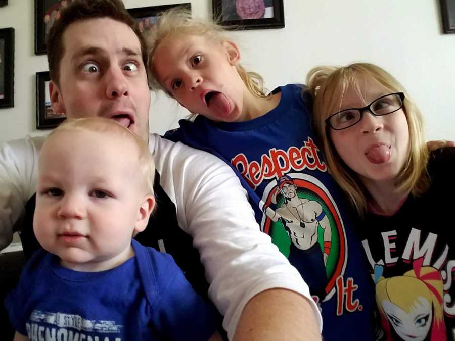 Active duty service member makes silly face in selfie with his baby son and two young daughters