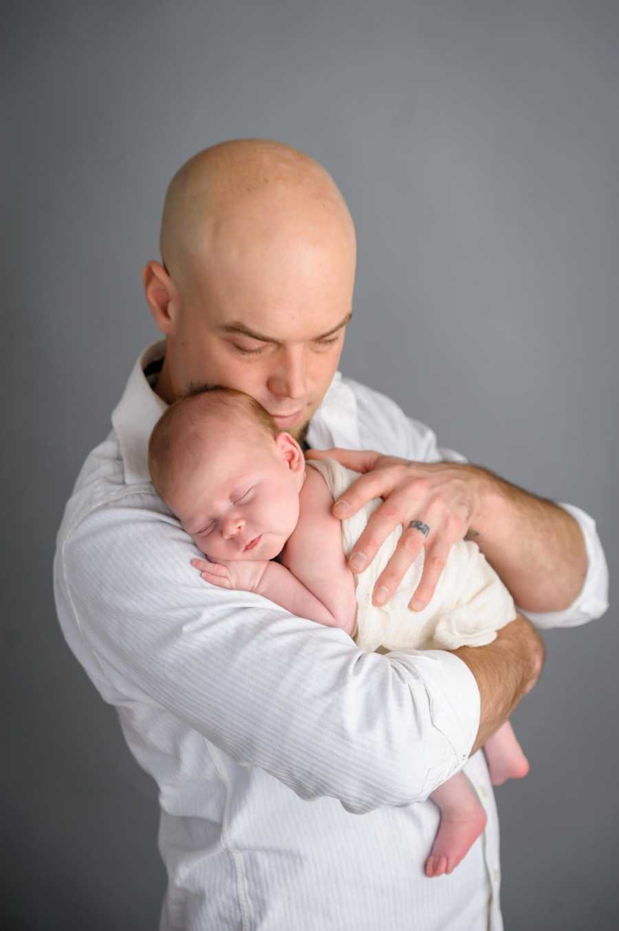 Father holds newborn who was conceived by egg donor in photoshoot