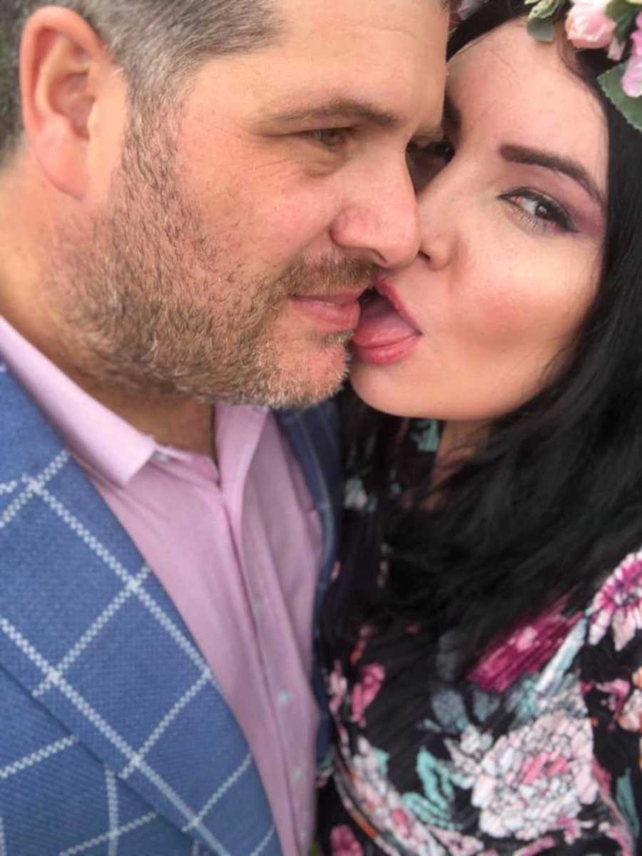 Wife sticks out tongue beside husbands face in selfie