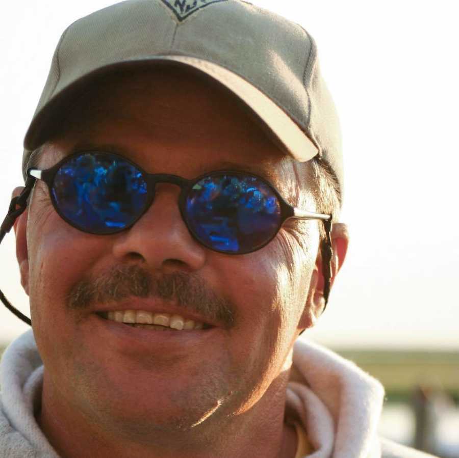 Man who has since passed away from cancer smiling with sunglasses and baseball hat on