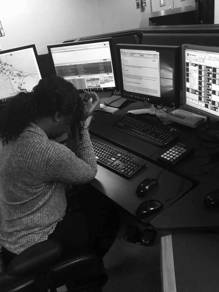 Woman who works as a dispatcher sits at desk with head rested on hands 