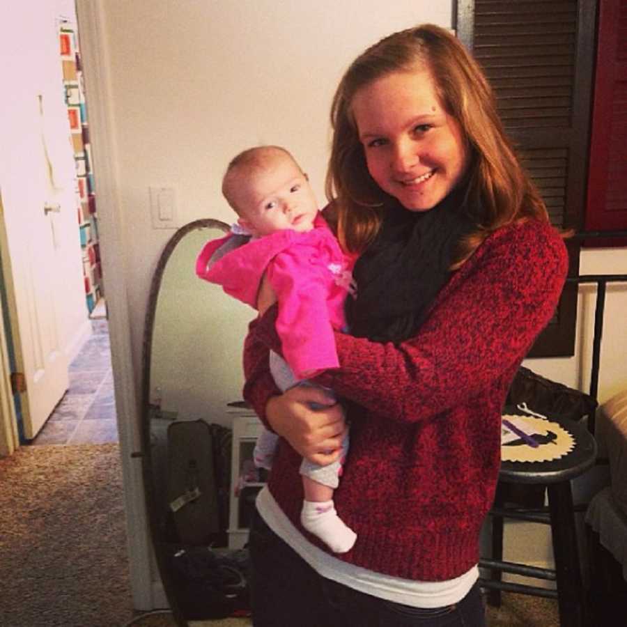 Mother smiles while holding baby daughter