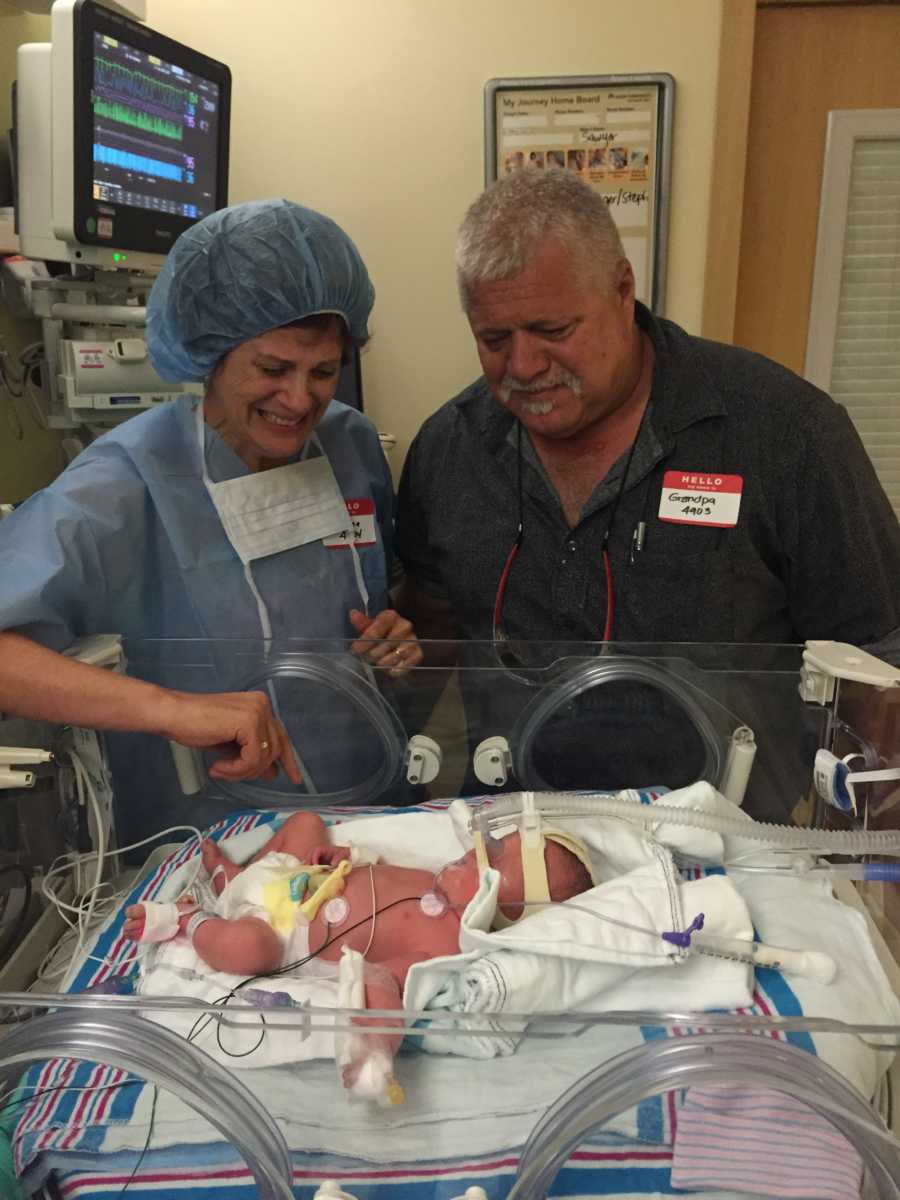 Grandmother and grandfather stands over grandchild in NICU