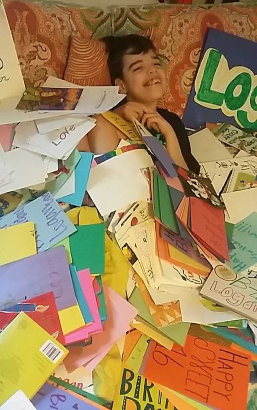 Young boy with severe uncontrollable epilepsy lays on couch with pile of birthday cards on top of him