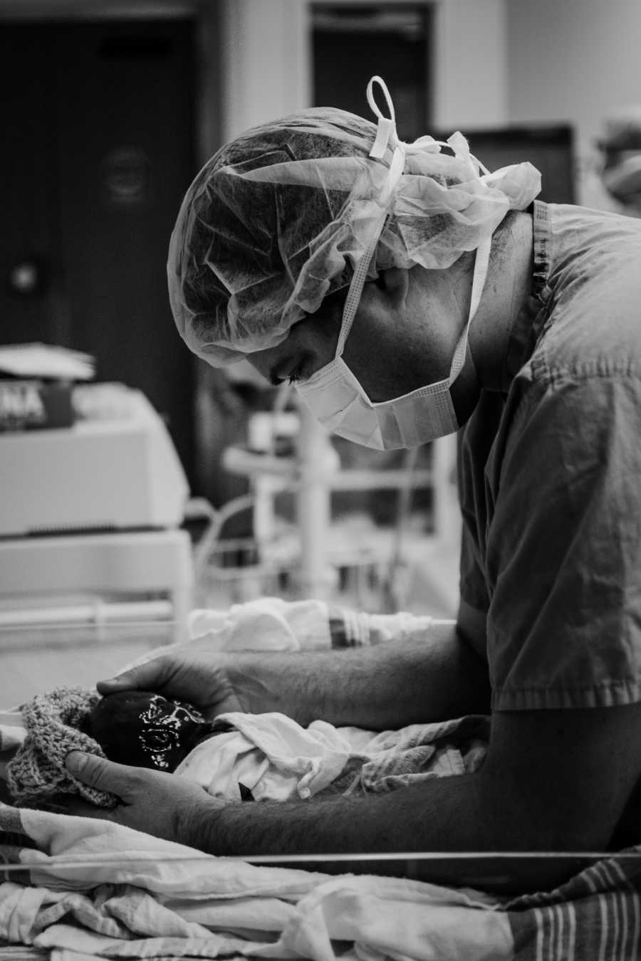 Father stands in hospital with arms around newborn son in heart failure