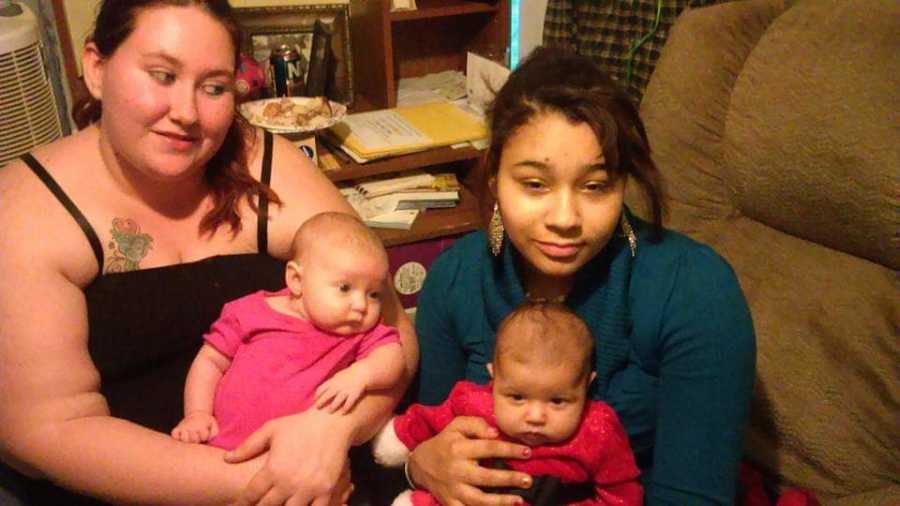 Cousins sit beside each other in home with their newborns sitting on their laps