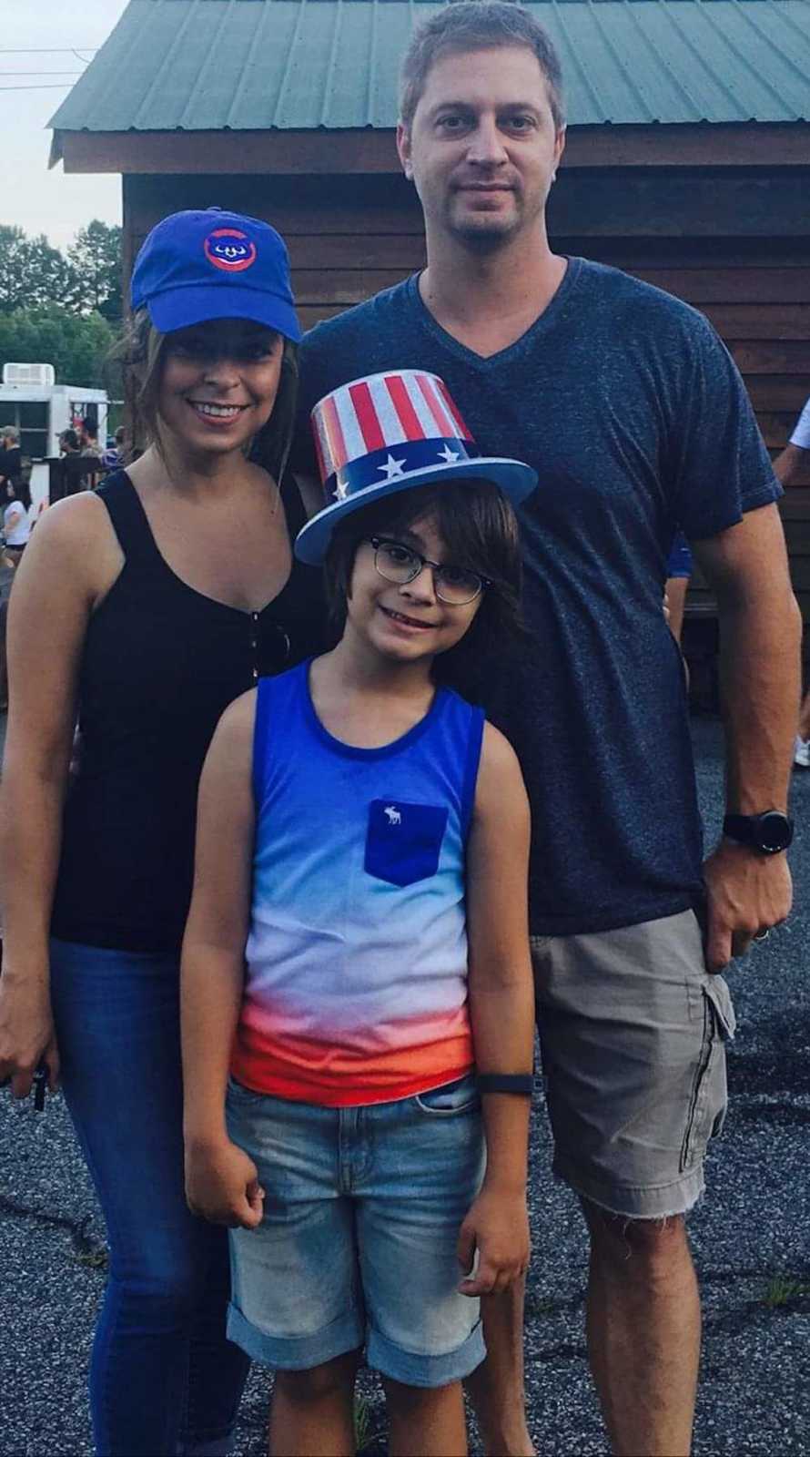 Man with depression stands smiling outside with wife and son