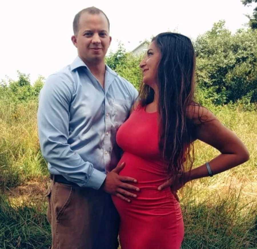 Pregnant woman stands outside looking at husband who is holding her stomach