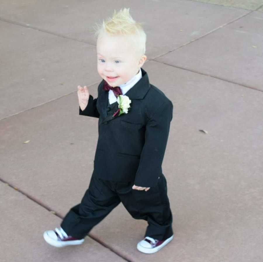 Little boy with down syndrome smiles while walking in suit