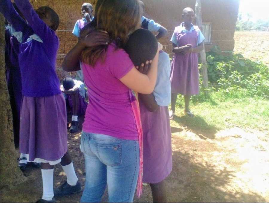 Teen standing outside hugging orphan from Kenya