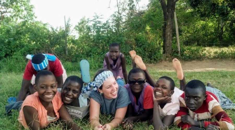 Teen lays on grass with Kenyan orphans beside her
