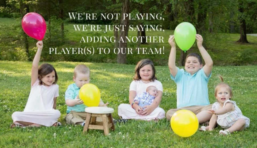 Six foster kids sit outside in matching outfits holding up balloons