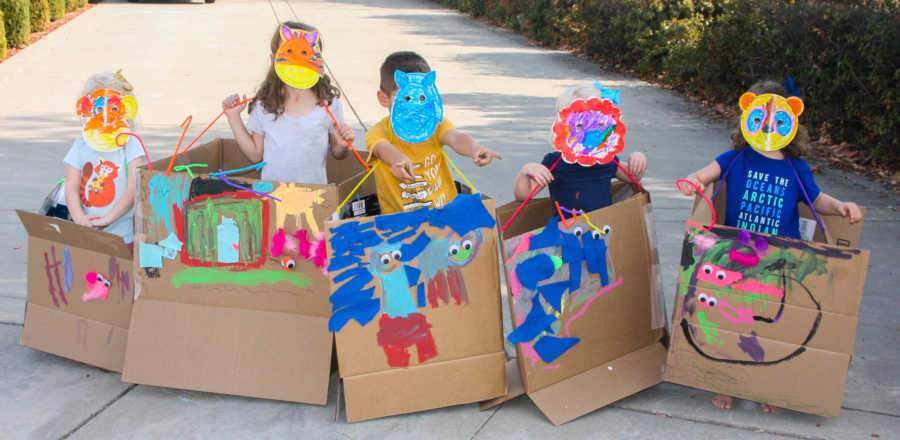 Five young siblings stand in driveway in decorated boxes and masks for Thanksgiving parade