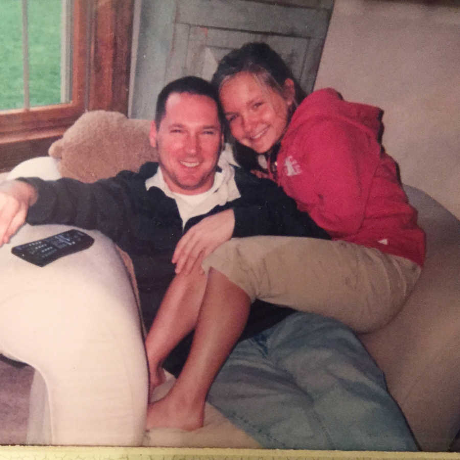 Father who will pass away at young age sits on couch with teen daughter sitting on his lap