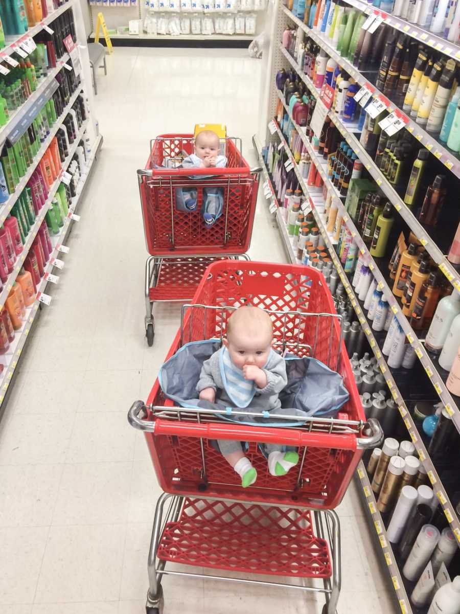 Two babies sitting in different shopping carts in hair care aisle of Target