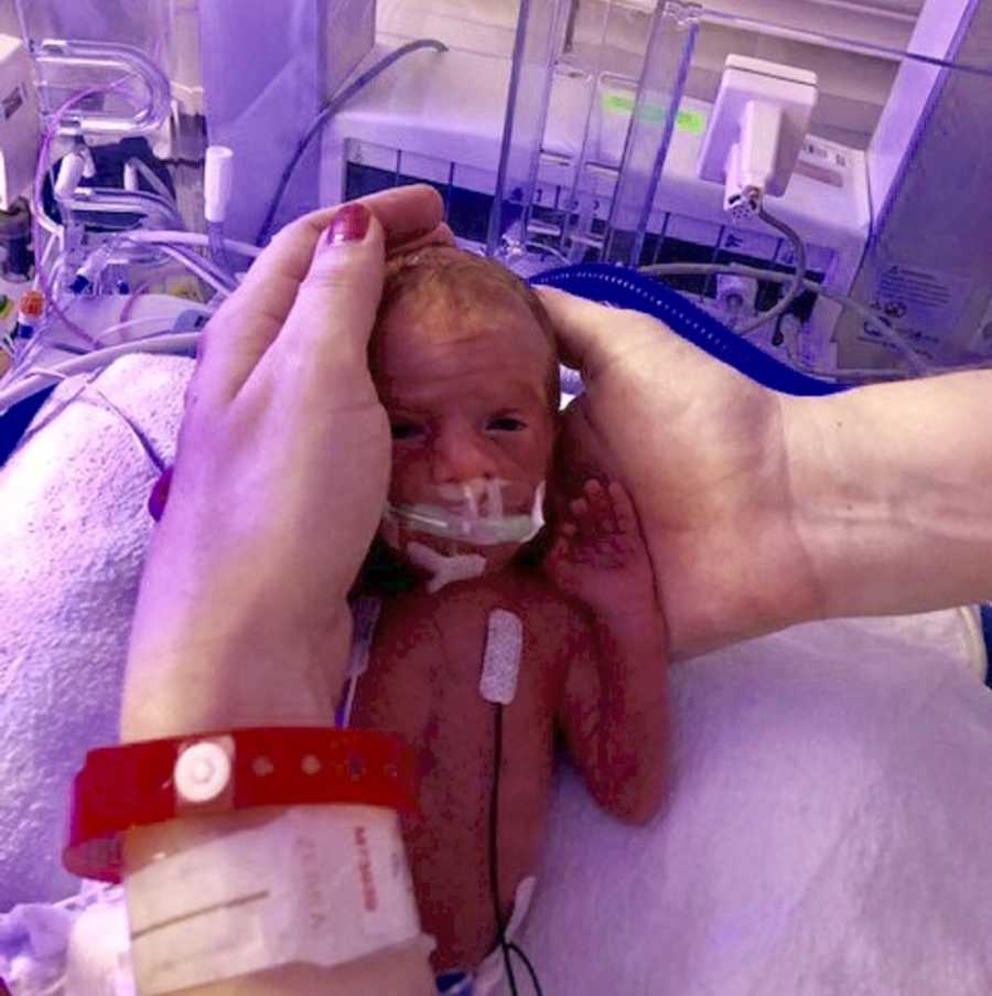 Preemie baby in NICU being held in woman's hands