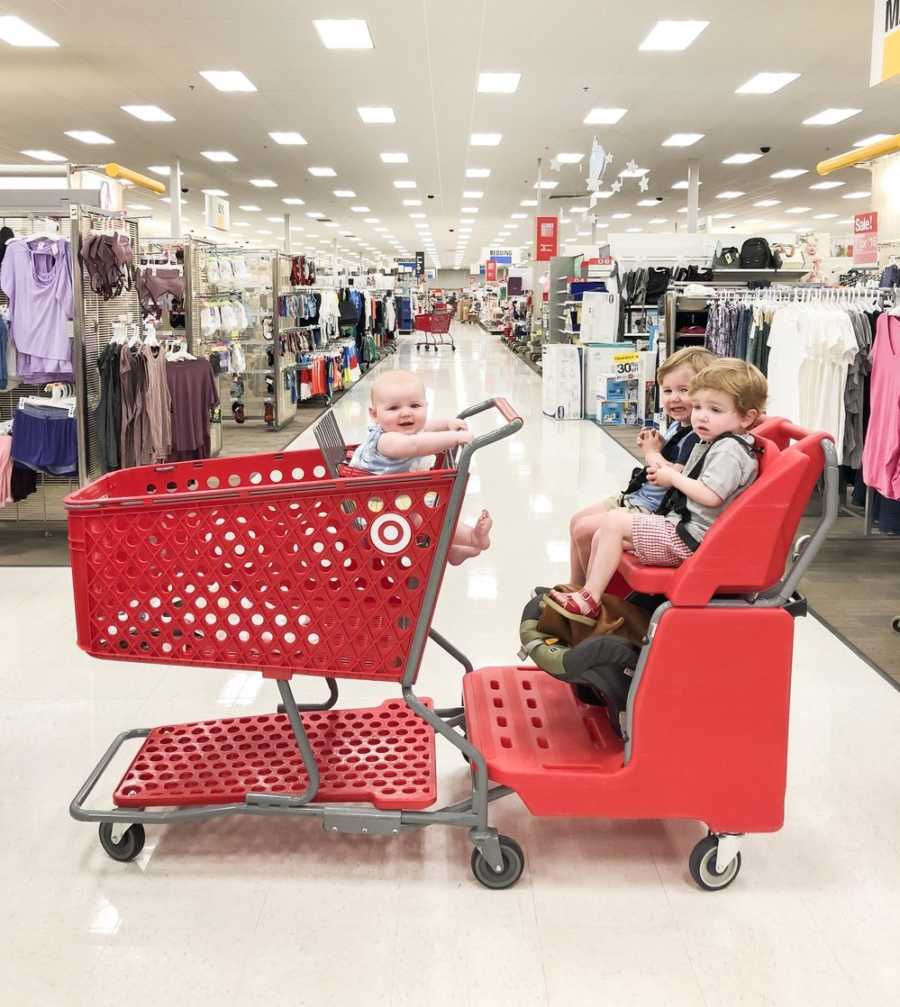 Toddler boys sitting in Target shopping cart with baby sister sits in another cart attached to it