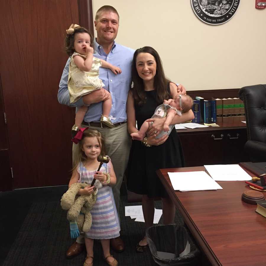 Husband and wife stand in adoption court with their adopted daughter and two biological daughters