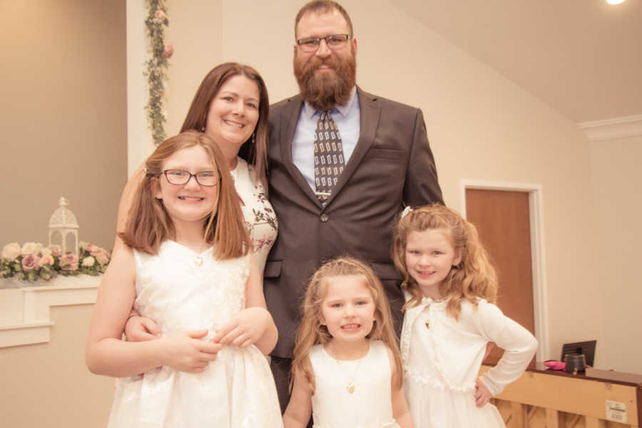 Woman who battled breast cancer stands smiling with husband and three children
