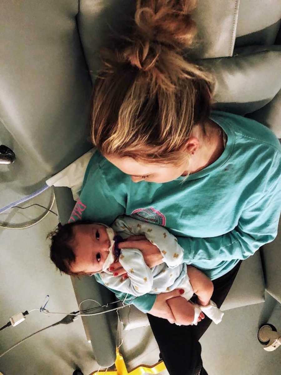 Aerial view of mother sitting in chair in hospital holding baby with RSV 