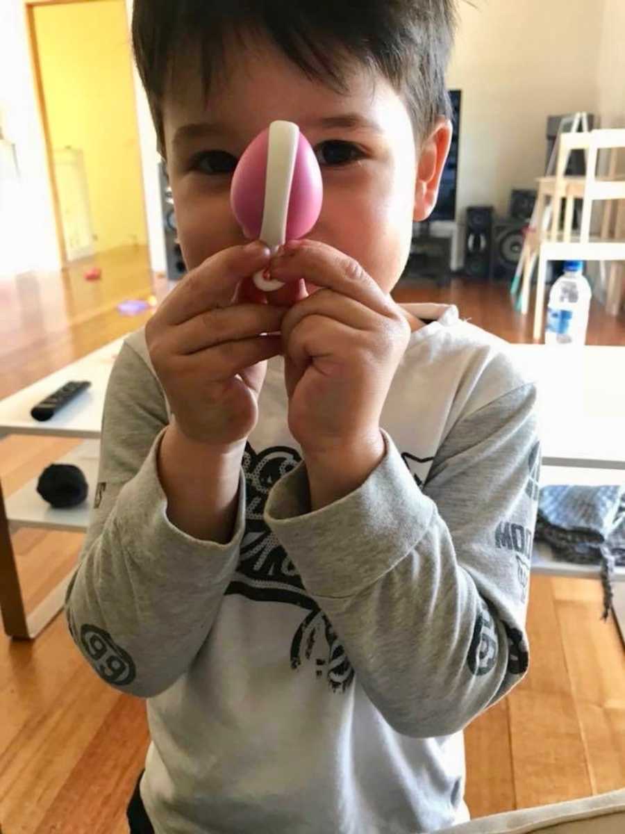 Little boy holds up mother's pelvic muscle weight in front of his face in home