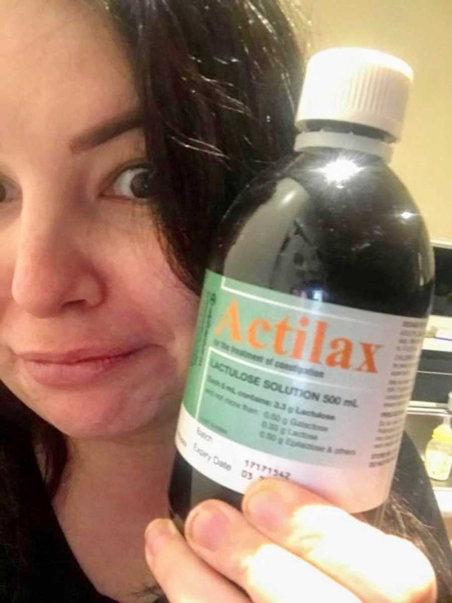 Selfie of woman holding up bottle of Actilax up beside her face