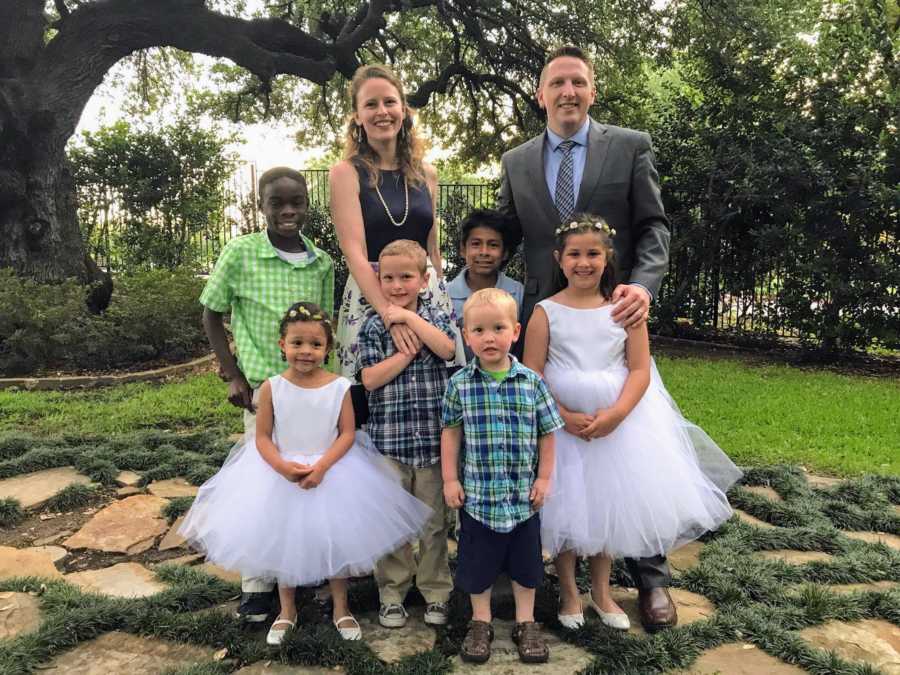 Husband and wife stand outside with their two biological sons and four foster children