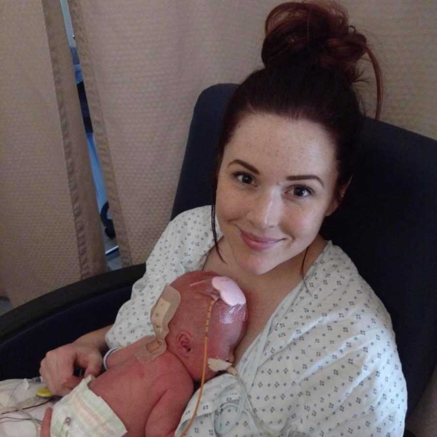 Mother sits smiling in NICU while newborn lays on her chest