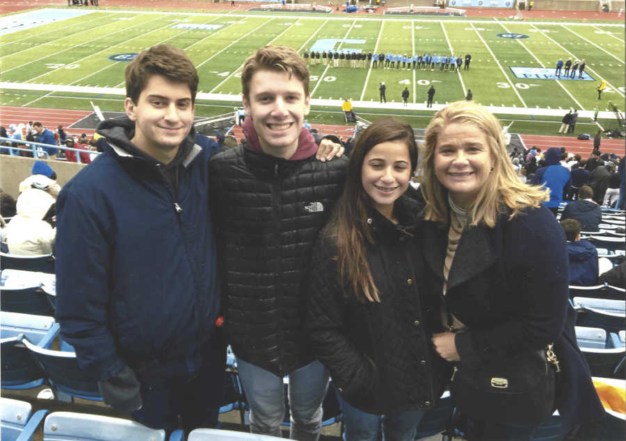 Wife whose husband passed from pancreatic cancer stands in football stadium with her three kids