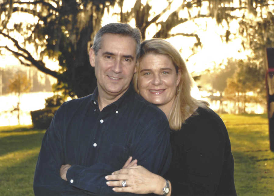 Husband with stage IV pancreatic cancer stands smiling with wife outside