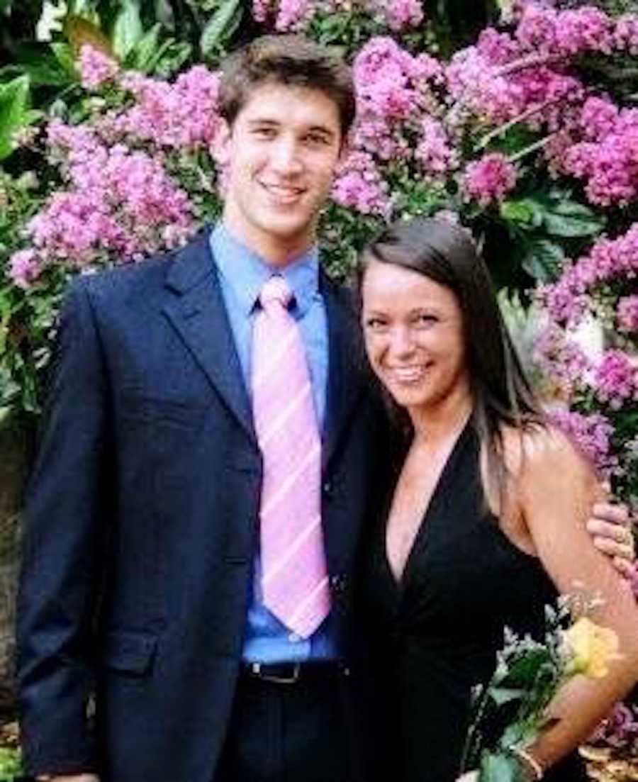 Young could stand arm in arm in formal clothing in front of bush of pink flowers