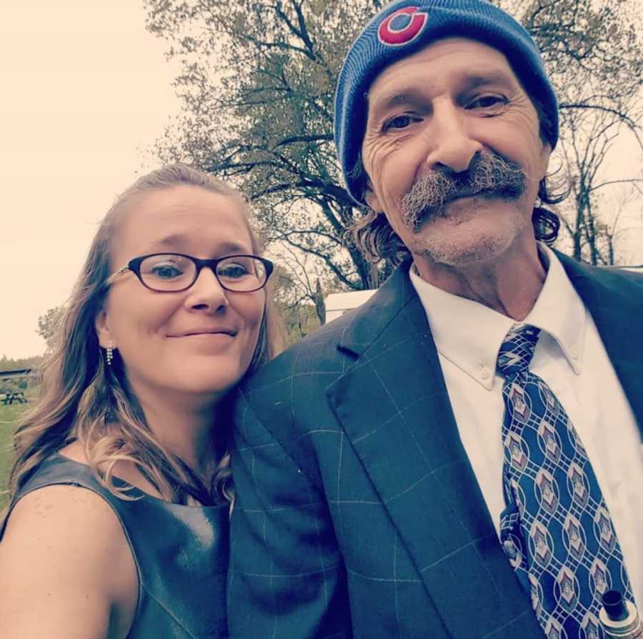 Young woman smiles beside father with lung cancer in selfie