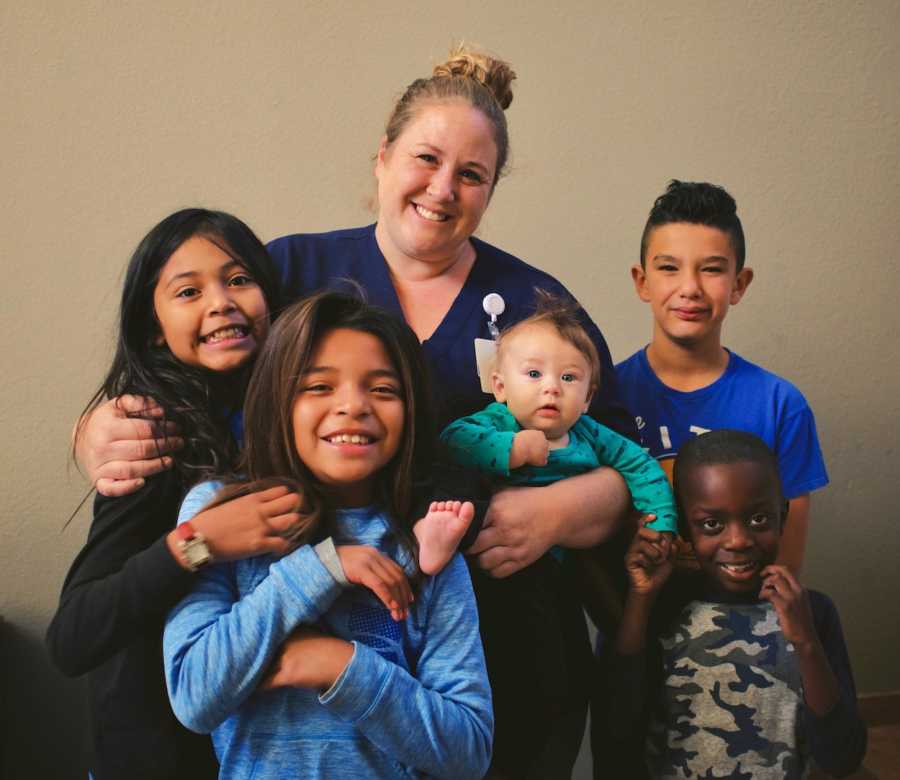 Nurse stands smiling with her five adopted children