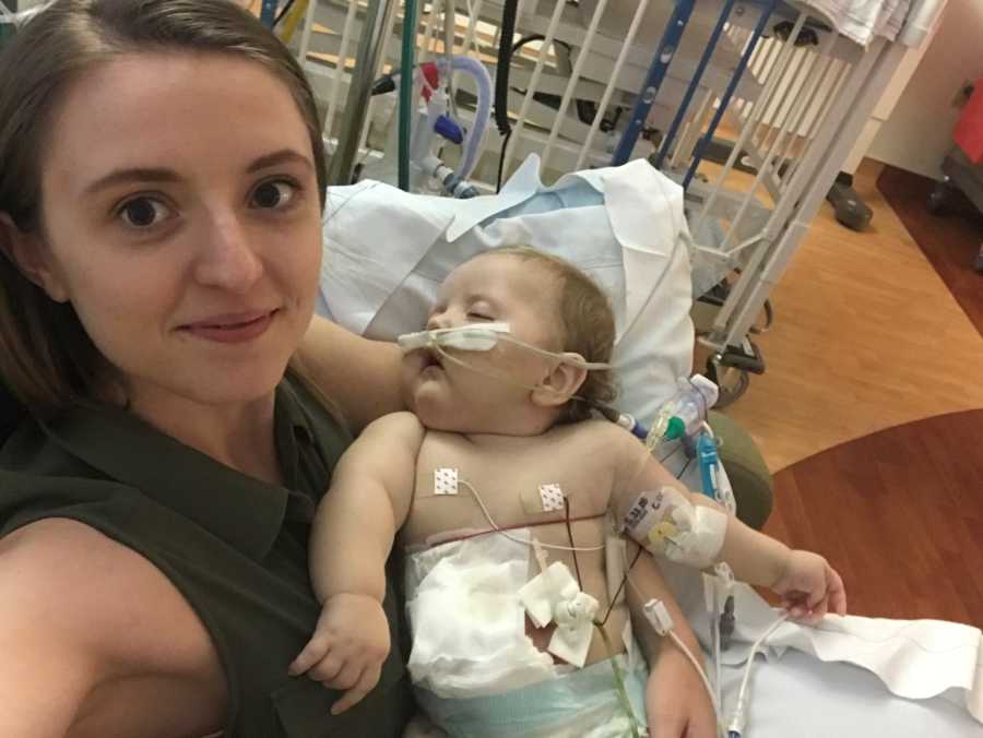 Mother smiles in selfie in hospital room as she sits holding baby with blindness, Cerebral Palsy, and Gastroparesis