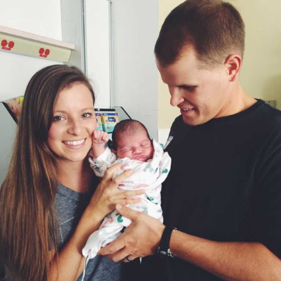 Husband and wife smiles as they hold newborn son they are adopting