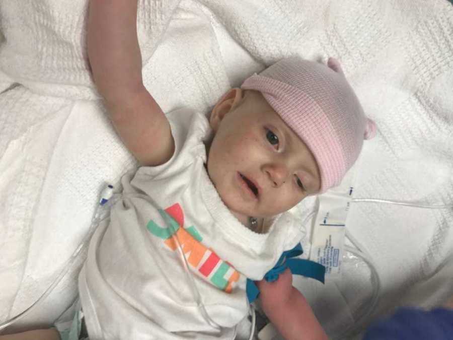 Baby with shaken baby syndrome lays in hospital with pink hat on