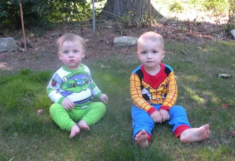 Best friends sons sits outside on ground in Buzz Lightyear and Woody outfits