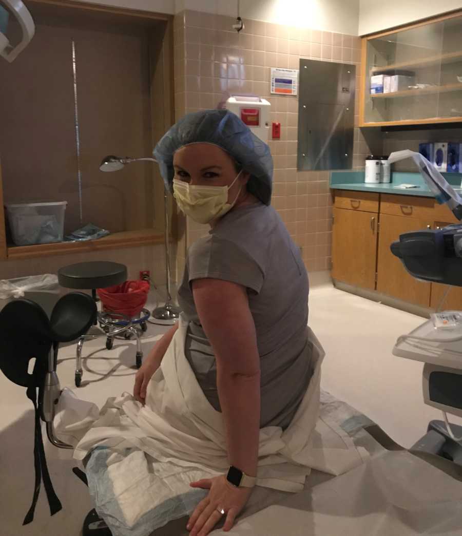 Woman wearing hair net and mask sits up in bed at fertility clinic