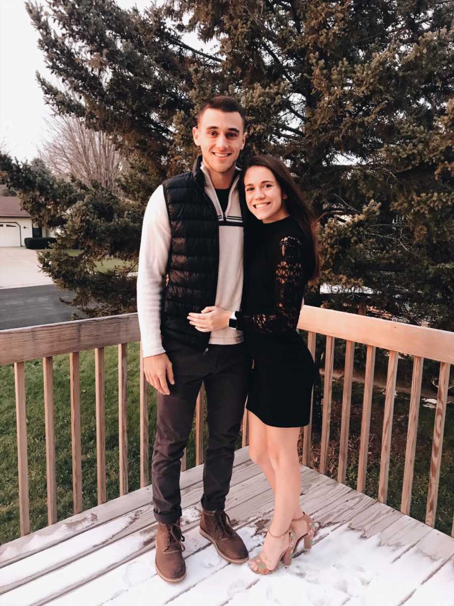 Young couple stand outside on wood porch