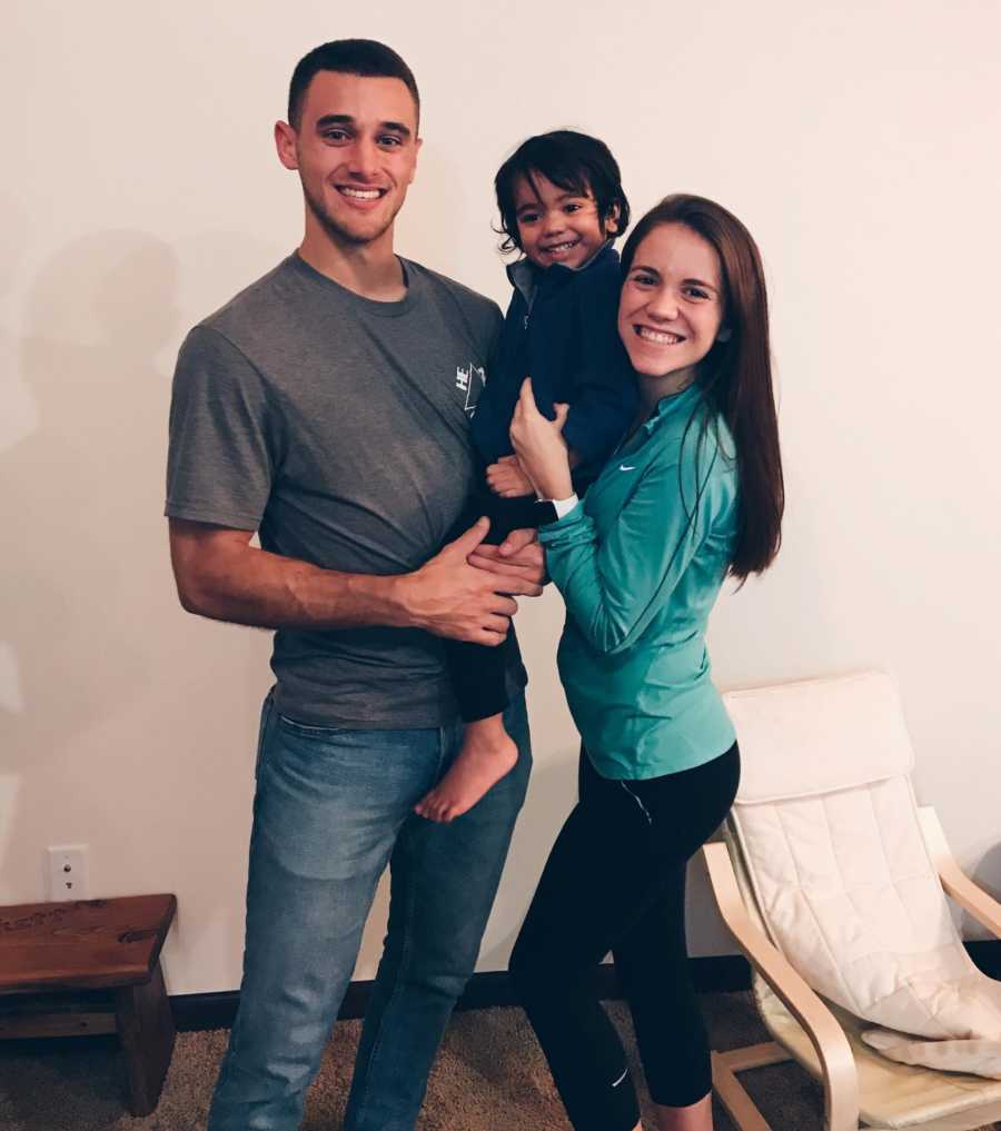 Single mother smiles beside her boyfriend as they hold her son